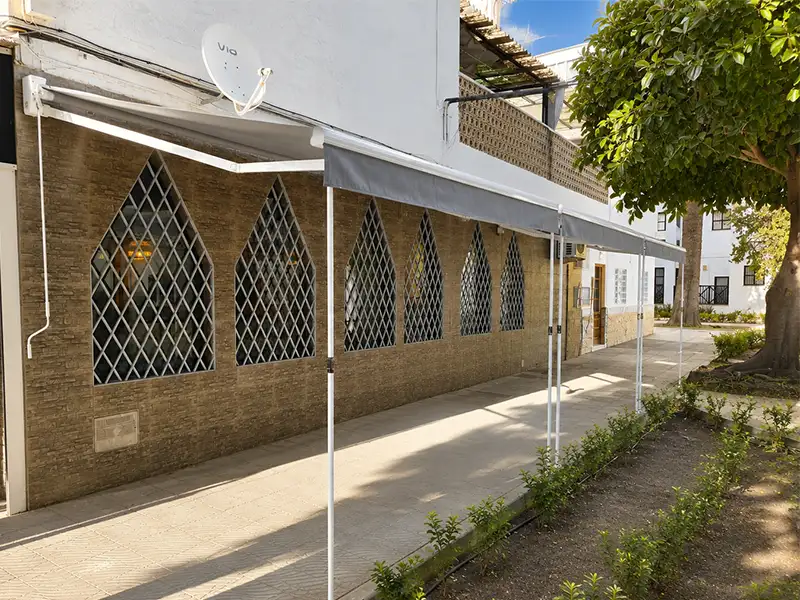 Toldo de brazos articulados con patas telescópicas en la terraza de un local de hostelería de Málaga