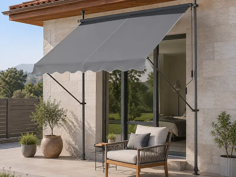 Toldo de brazos articulados con patas telescópicas y lona gris en una terraza de la costa de Granada