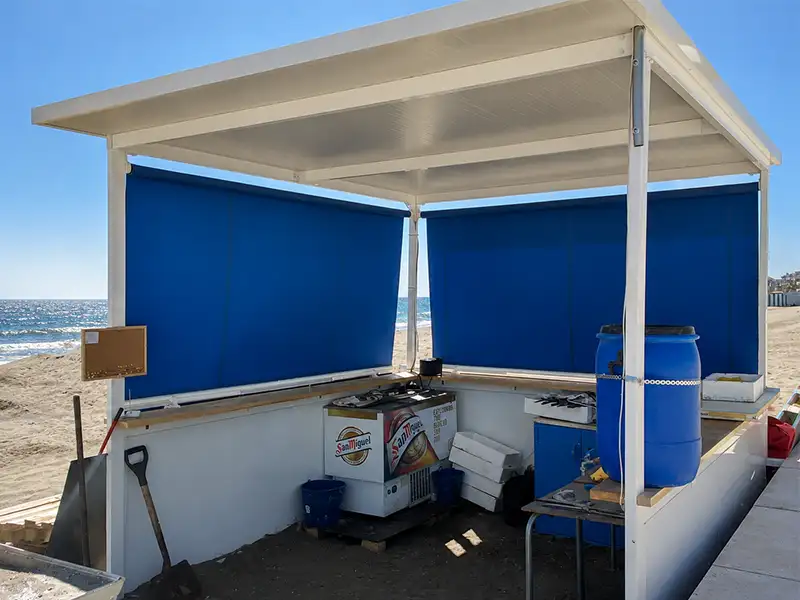 Toldo stor de lona azul dando sombra en un chiringuito de playa de la costa de Málaga