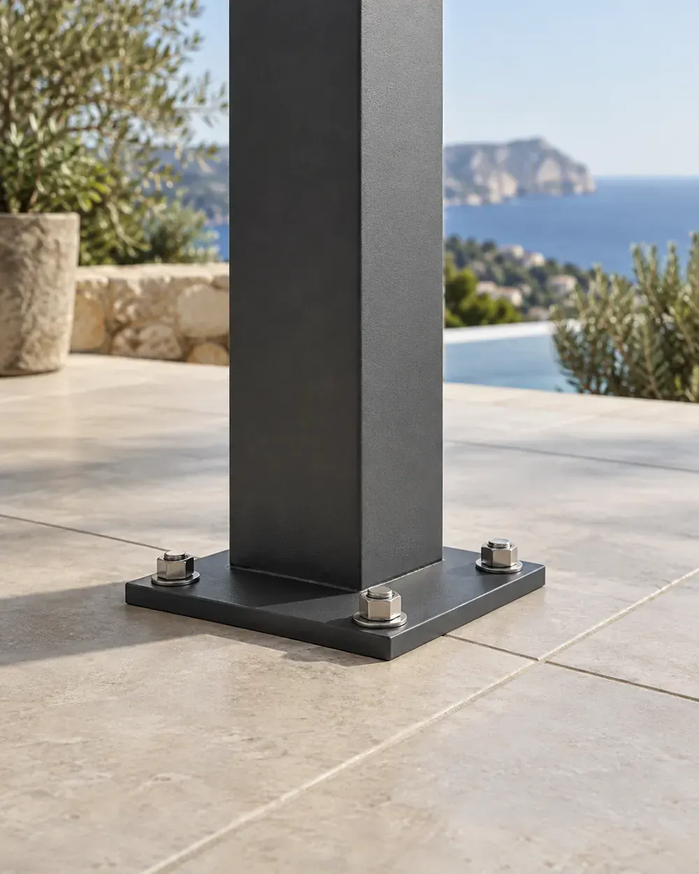 Anclaje de pilar de pérgola Anclaje con tornillería inoxidable del pilar de una pérgola de aluminio antracita sobre el suelo de una terraza