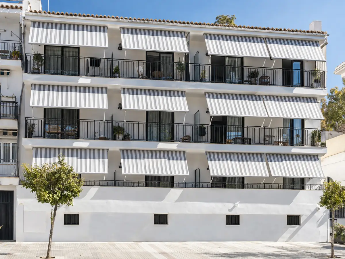 Cambio de lonas en comunidades Fachada de una comunidad de vecinos con las lonas de rayas de los toldos renovadas