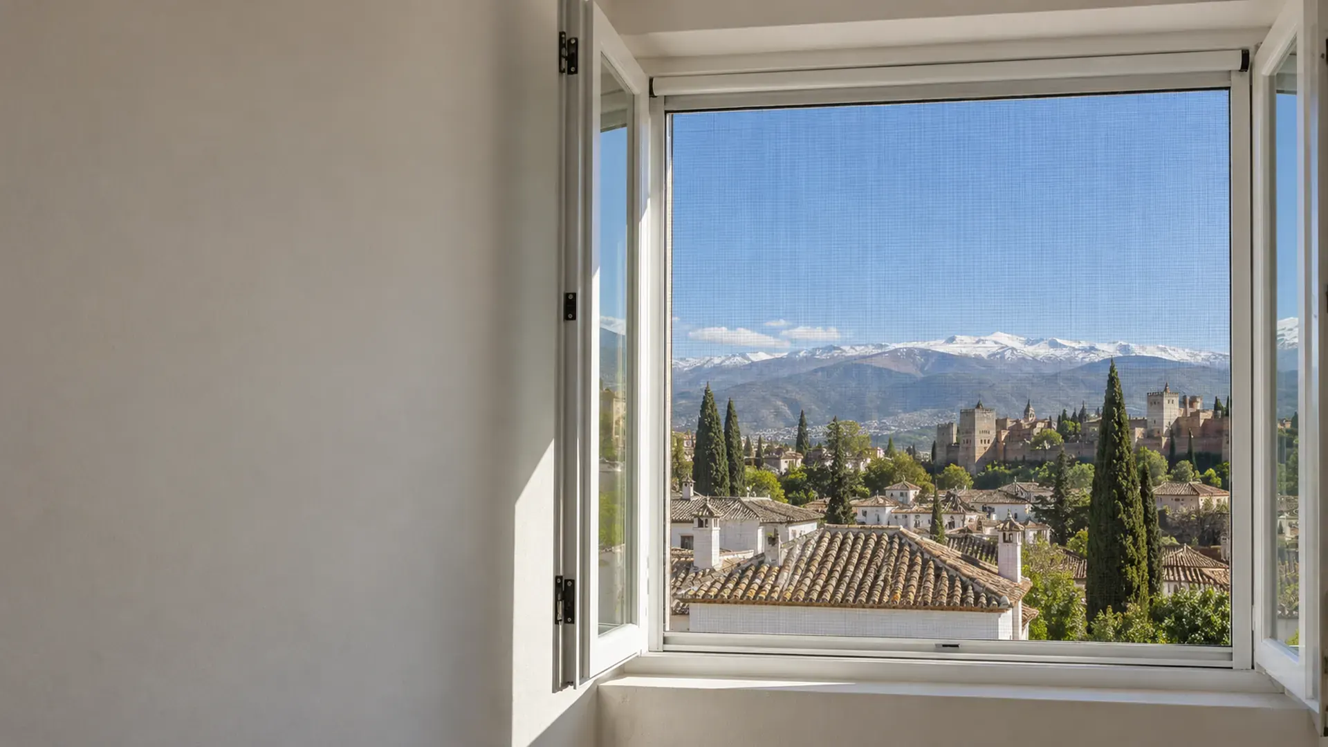 Mosquiteras en Granada: mosquitera enrollable en la ventana de una casa con vistas a la Alhambra y Sierra Nevada