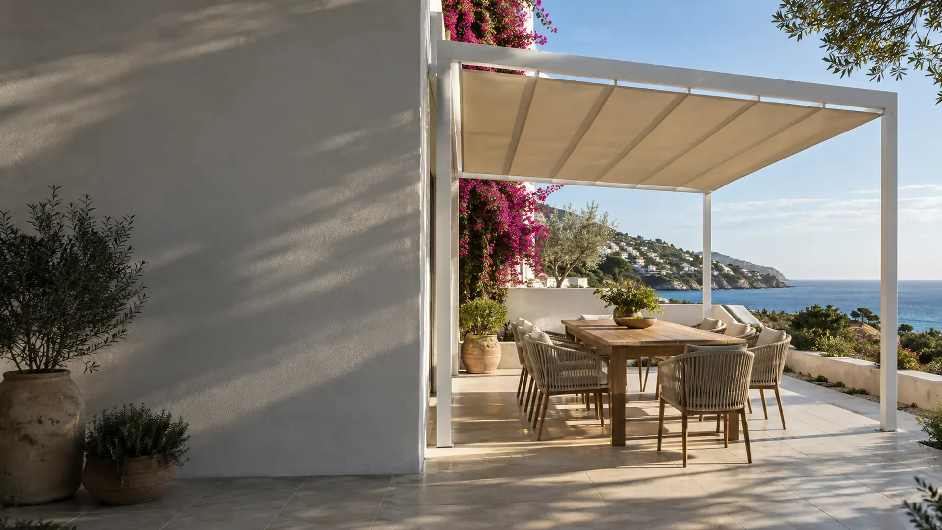 Pérgola de aluminio en Málaga con toldo corredero de lona crema sobre el comedor exterior de una casa con vistas al mar