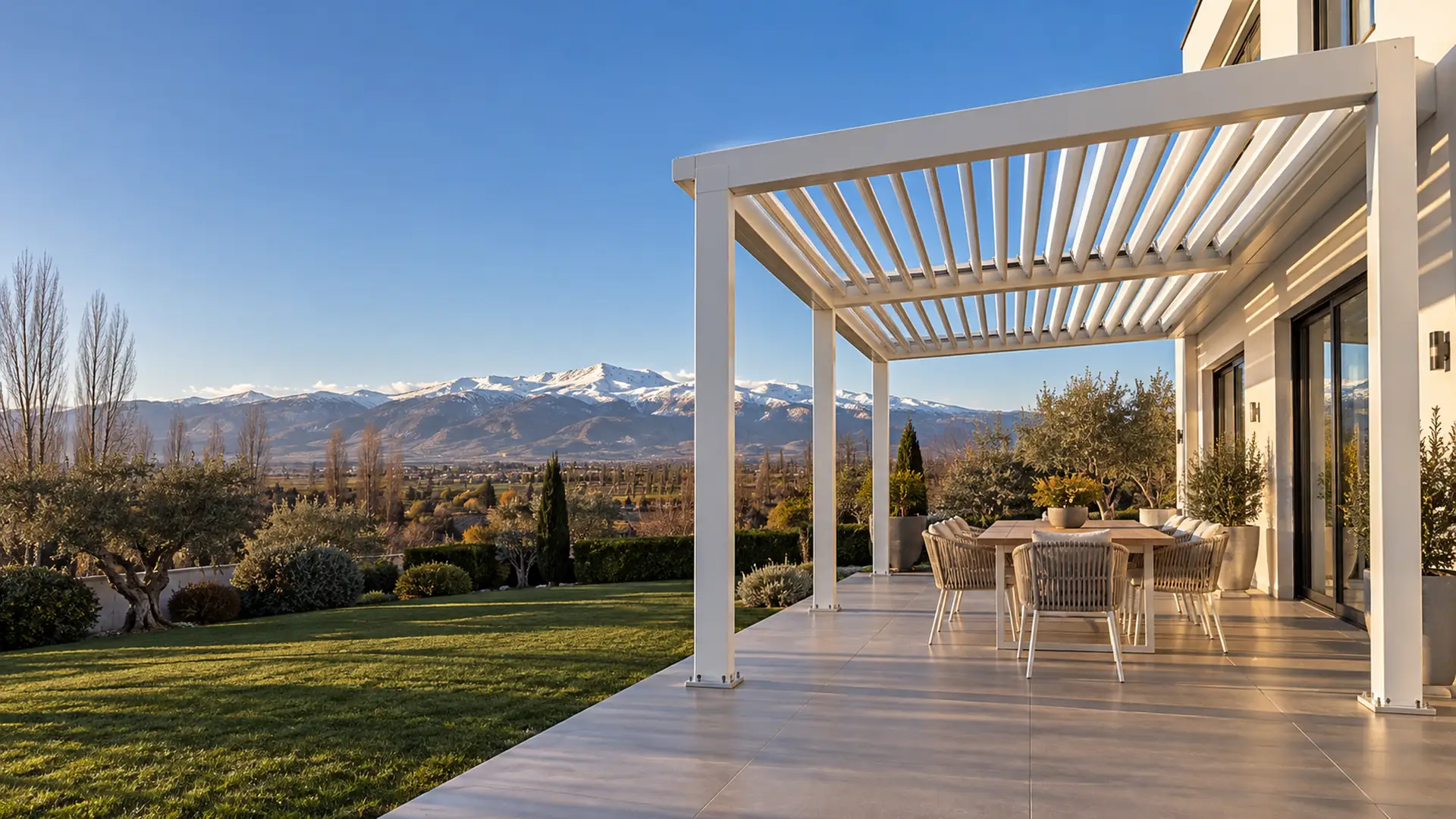 Pérgolas bioclimáticas en Granada Pérgolas bioclimáticas en Granada: pérgola de lamas orientables en el jardín de un chalet con Sierra Nevada al fondo