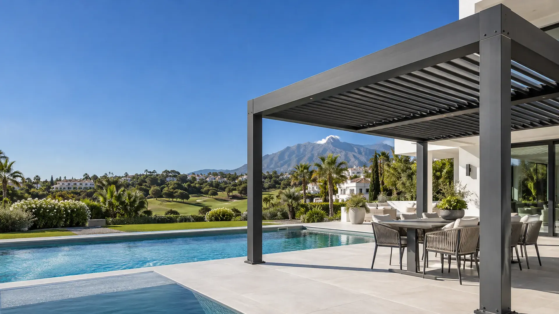 Pérgolas en Marbella: pérgola bioclimática antracita junto a la piscina de una villa con La Concha al fondo