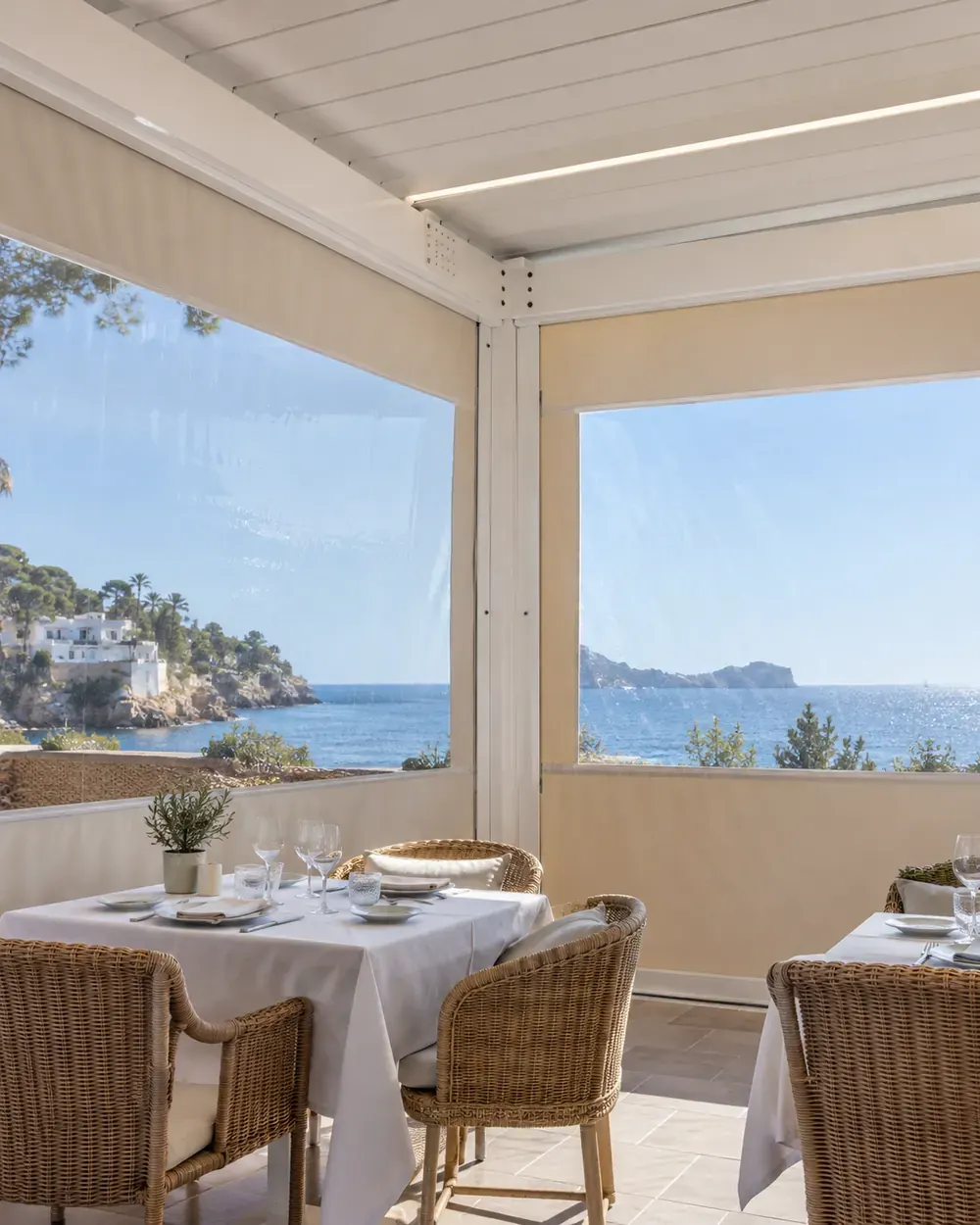 Terraza de hostelería con cortavientos Terraza de restaurante cerrada con estructura de aluminio y cortavientos con ventanas transparentes y vistas al mar