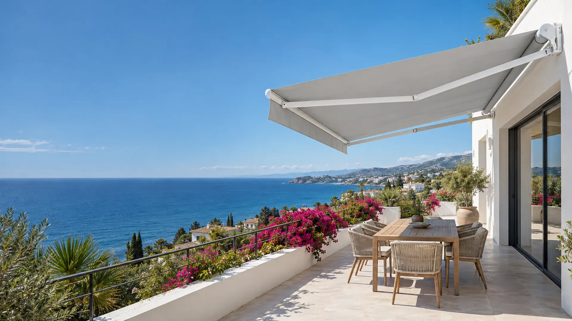 Toldo articulado en Málaga con lona gris extendido sobre la terraza de una vivienda con vistas al mar
