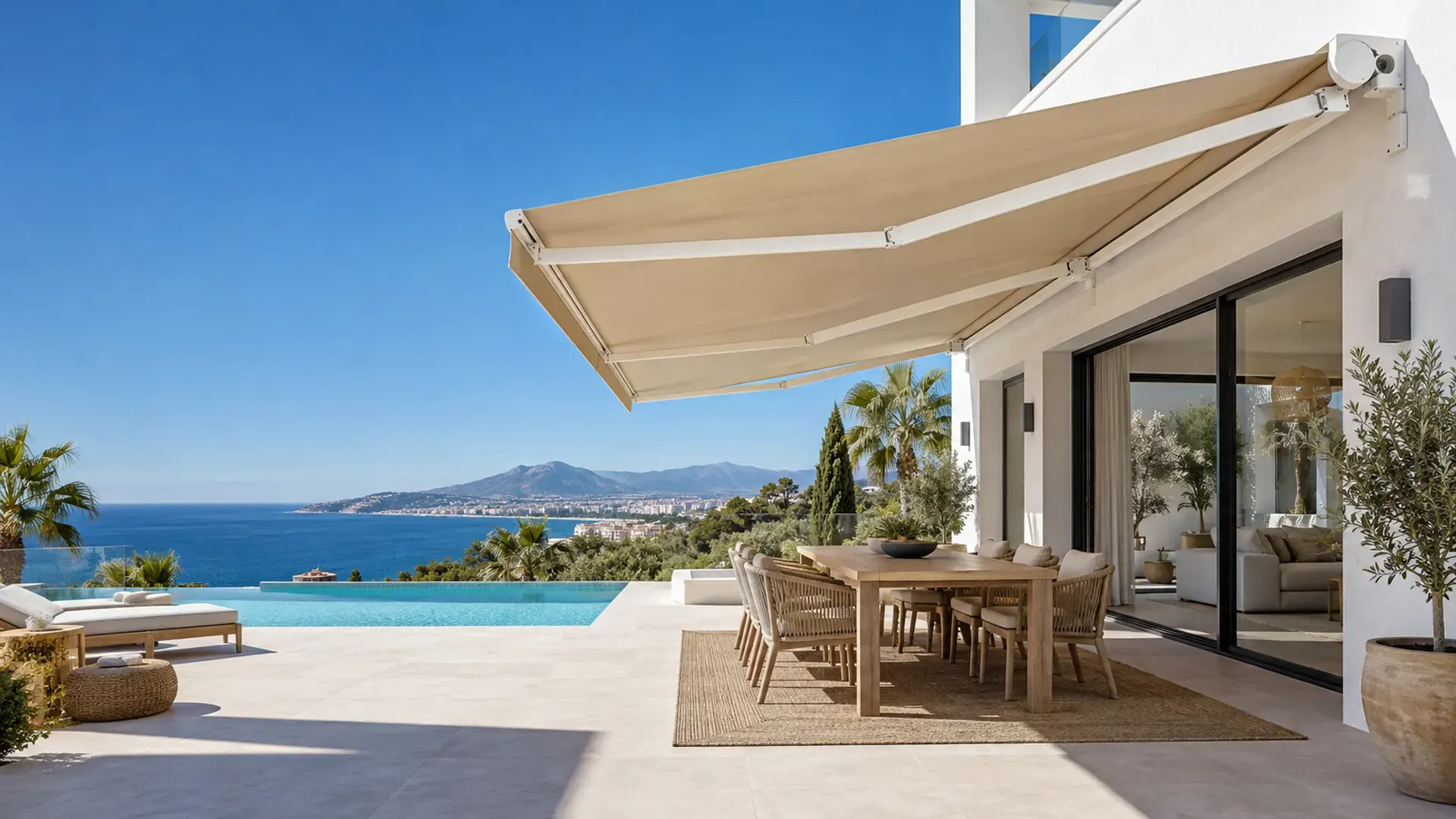 Toldo monobloc en Málaga: toldo de gran tamaño con lona color arena sobre el comedor exterior de un chalet con piscina y vistas al mar