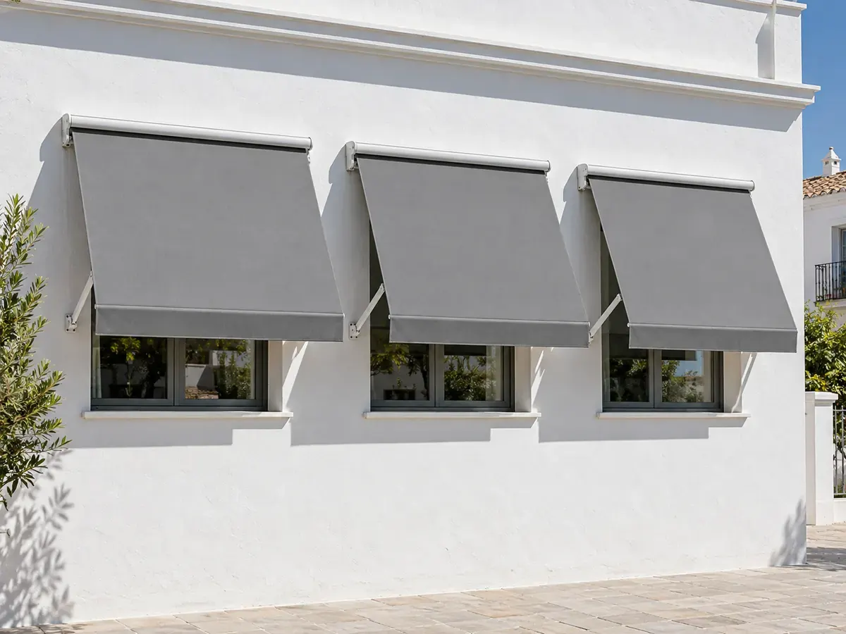 Toldo punto recto motorizado Toldos punto recto motorizados con lona gris en tres ventanas de una vivienda en Málaga