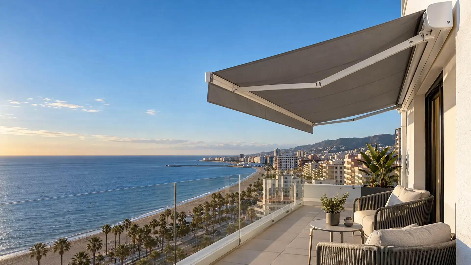 Toldos en Fuengirola: toldo cofre con lona gris en la terraza de un piso con vistas a la playa y el paseo marítimo