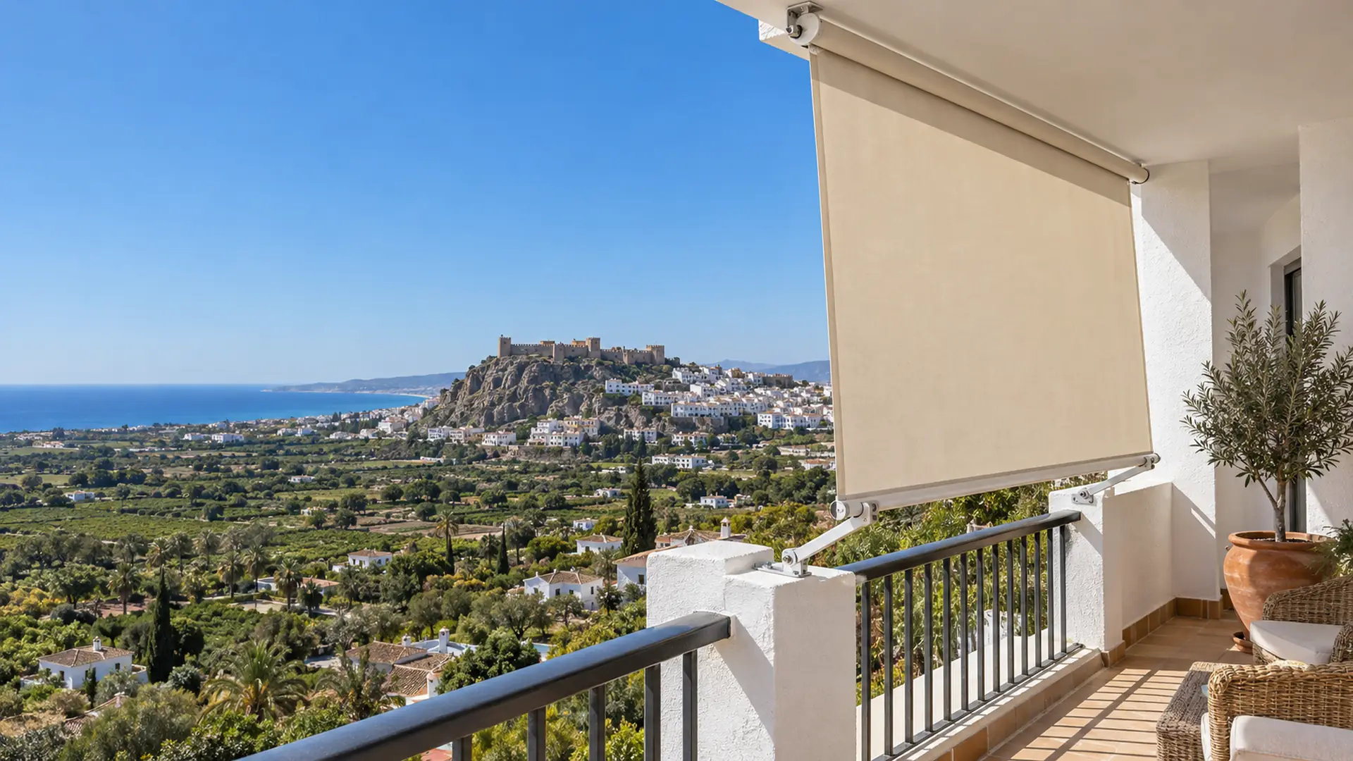 Toldos en Salobreña: toldo stor en la terraza de una casa blanca con vistas al castillo